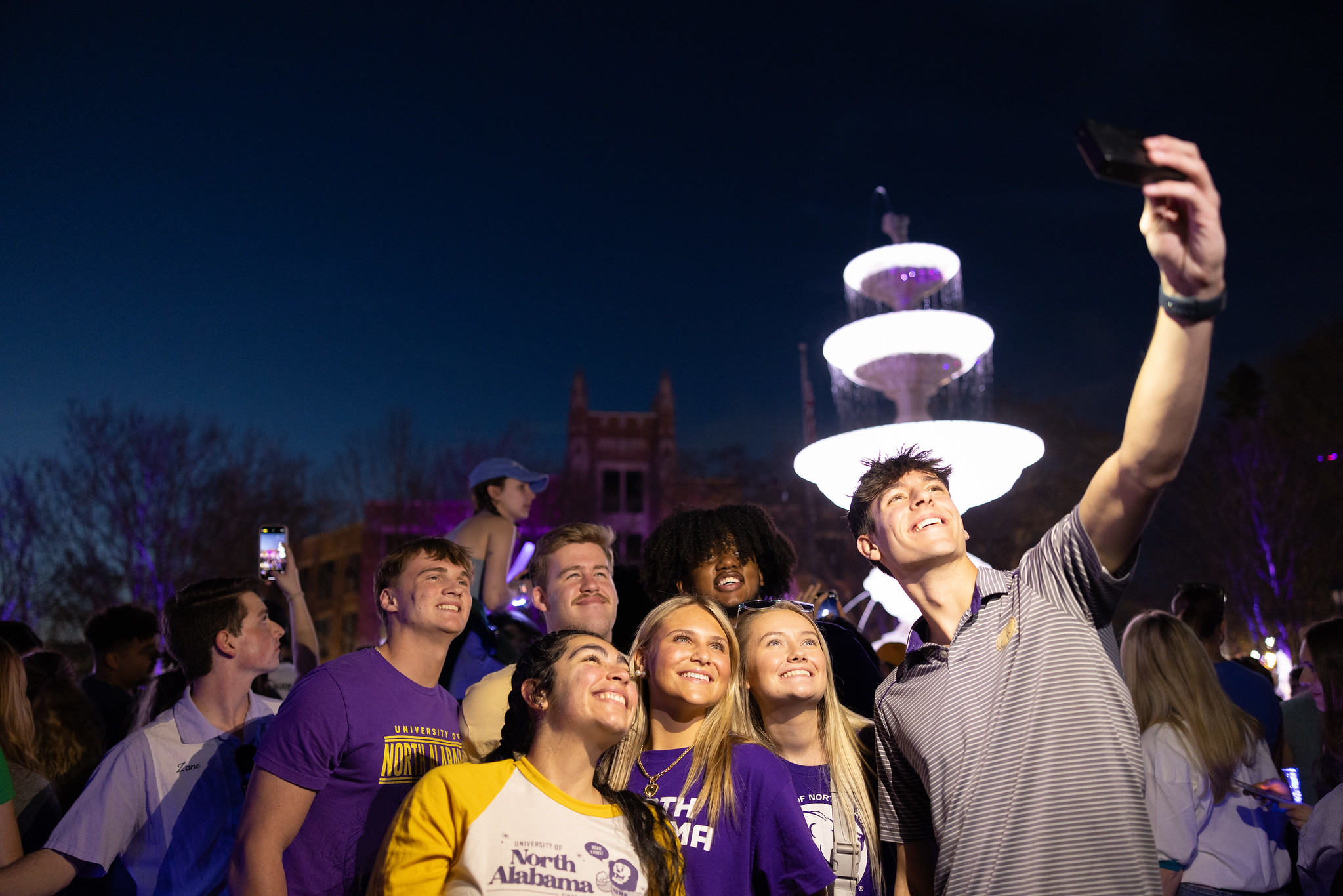 Students taking a group selfie in front of the Harrison Plaza fountain.